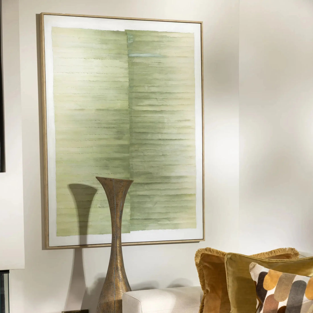 An abstract framed wall art print featuring textured horizontal brushstrokes in muted sage green, olive, and cream tones, enclosed in a thin light brown frame.