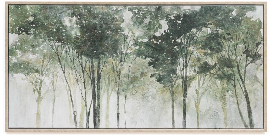 A framed horizontal canvas print depicting a misty forest with tall trees in soft shades of green, gray, and white, set in a light natural wood frame.