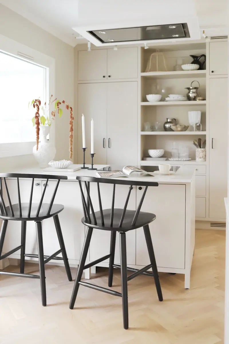 Modern kitchen with white cabinets, black chairs, and a white island.
