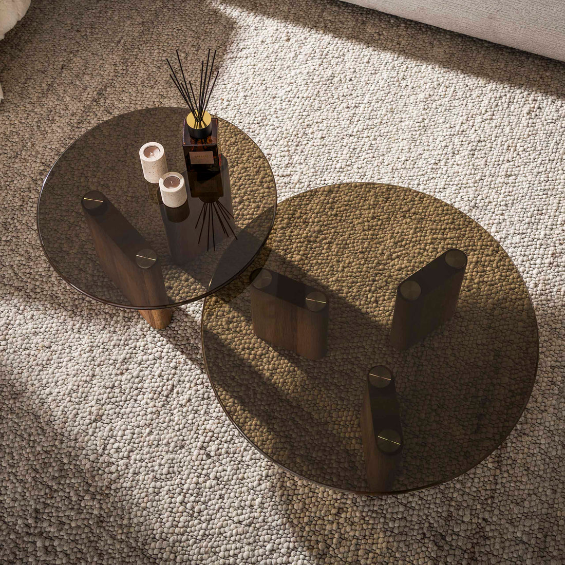 Two round glass coffee tables with wooden bases on a white background