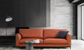 An orange leather sofa in a modern living room setting with a black floor lamp, a round glass coffee table, and a textured gray wall background.