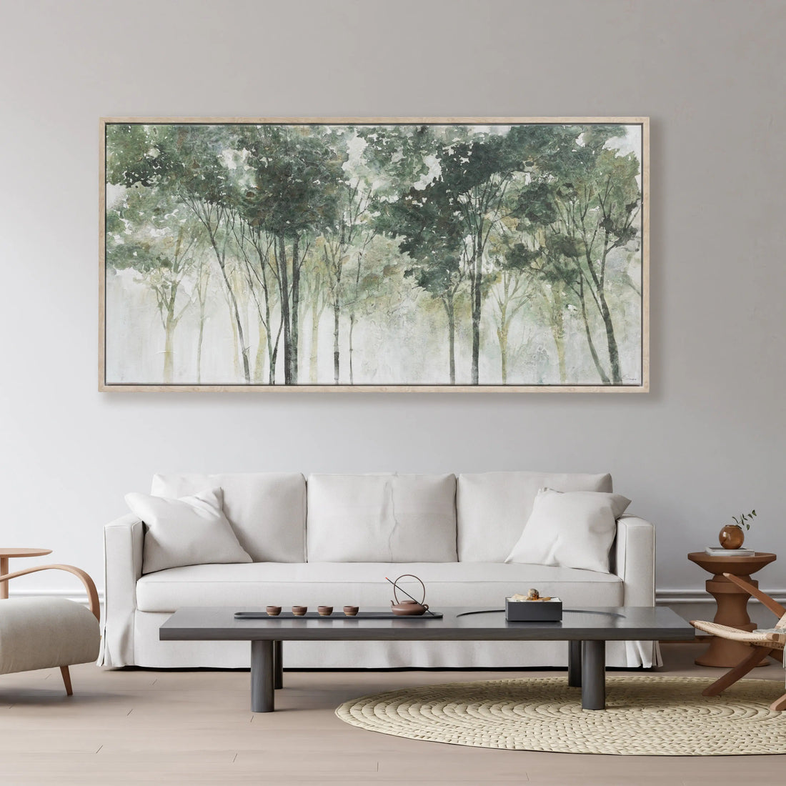A framed horizontal canvas print depicting a misty forest with tall trees in soft shades of green, gray, and white, set in a light natural wood frame.