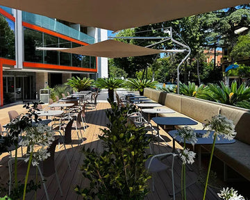 Outdoor dining area with tables, chairs, and a modern building in the background.