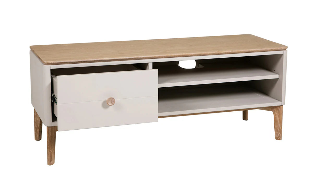 A modern low TV stand or media console with a light natural wood top and legs, and a white cabinet body featuring one open drawer and two open shelves.