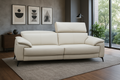 Beige sofa in a living room with framed art on the wall and a window in the background.